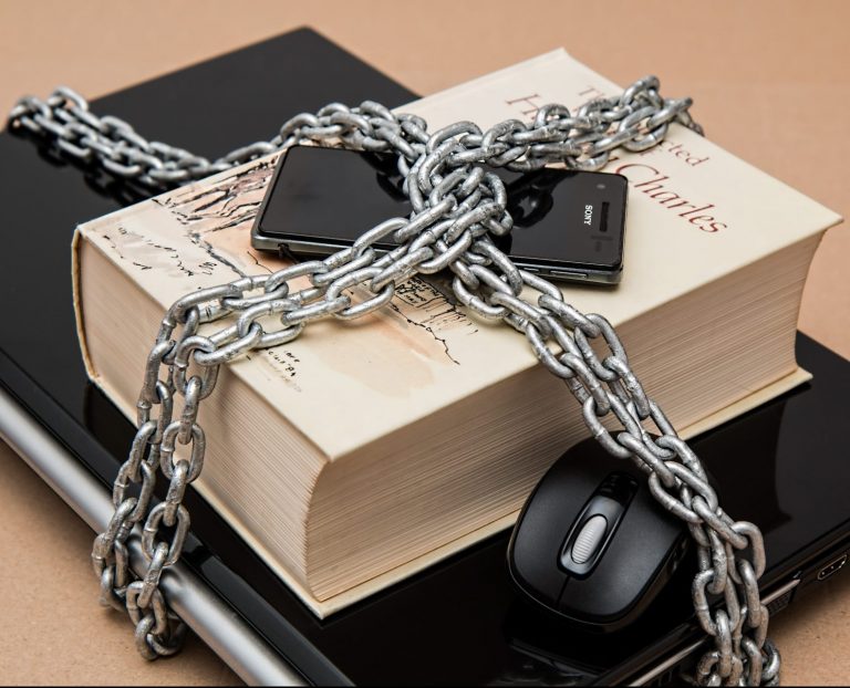 Ordinateur, téléphone et livre enchainés et cadenassés
